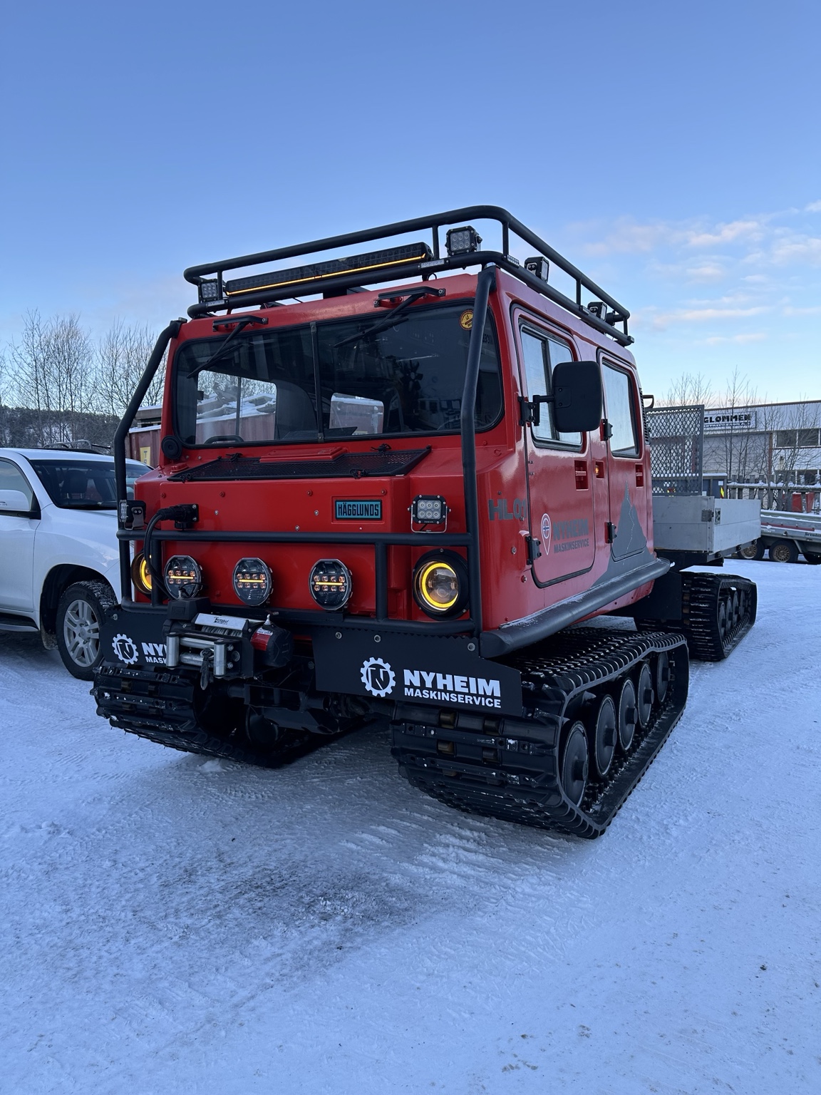Ferdig gjenoppbygd rød Hägglunds BV206 med takgrind og arbeidslys.
