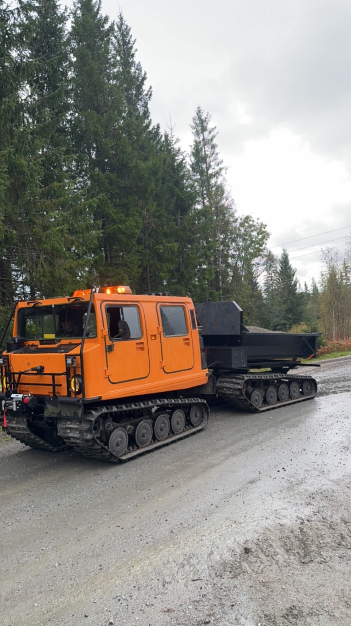 Oransje HL04 Hägglunds BV206 D5 med tippflak på skogsvei